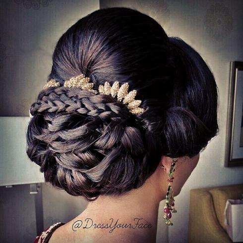 bridal updo featuring a low sculptured bun and braids placed under the dome to prop-up the accessories